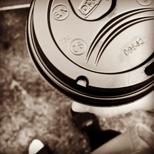 Photo of a travel coffee cup with a black plastic lid.